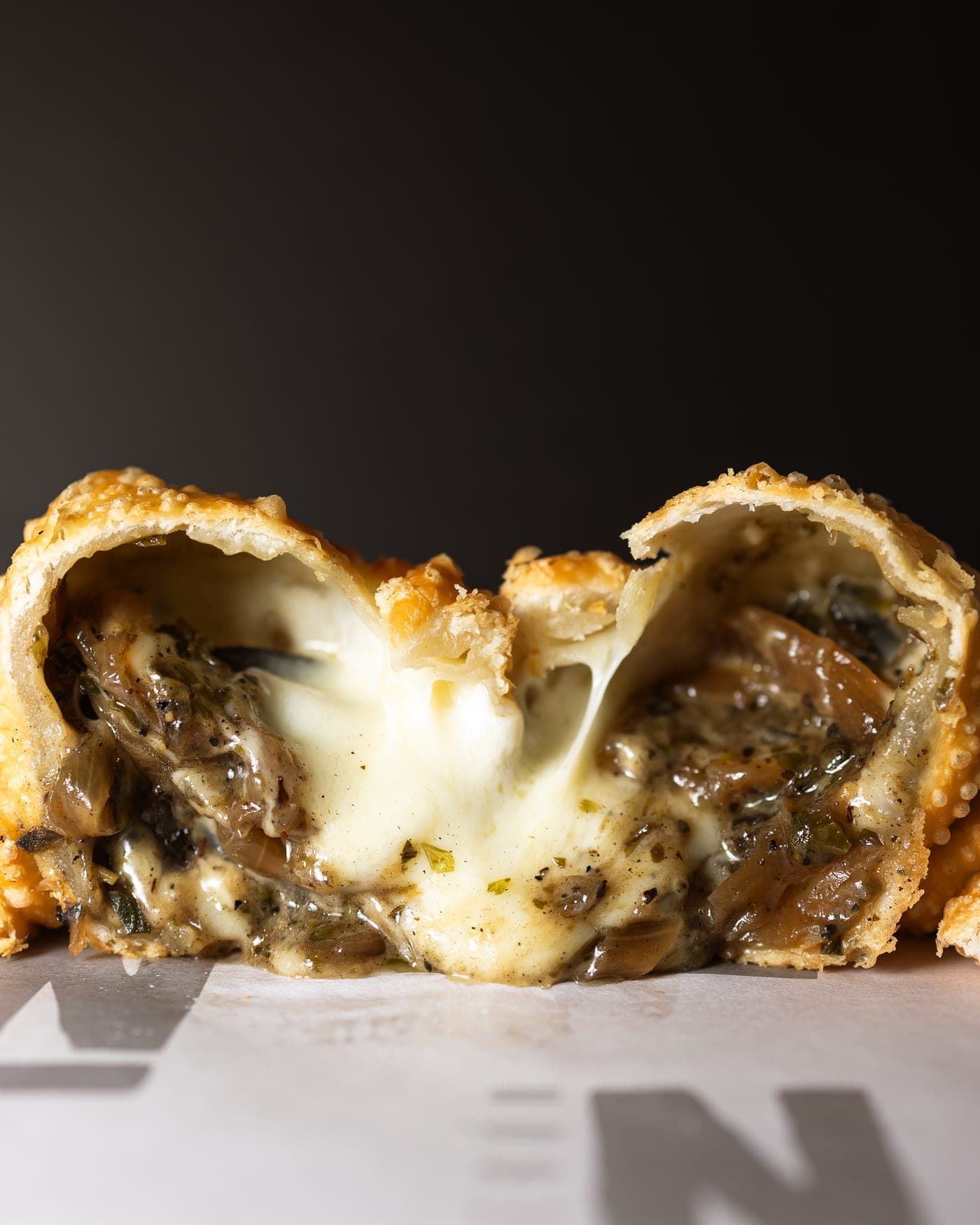 Empanada abierta con queso fundido y hierbas